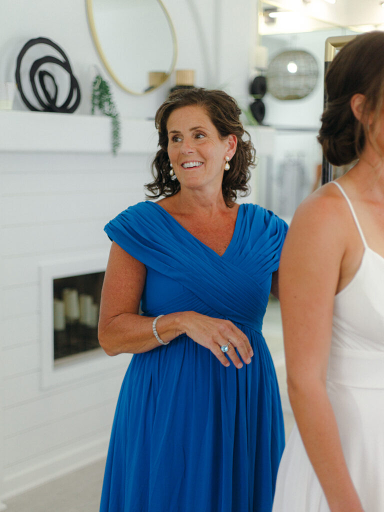 Mother helping daughter with wedding dress buttons. Wedding day moments with mom